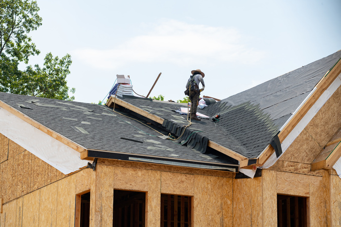 worker Installing asphalt roofing shingles while roof replacement